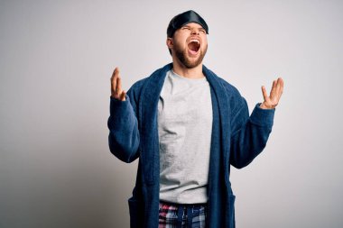 Sakallı, mavi gözlü, pijamalı, deli deli deli bağıran, sinirli ifadeli ve kolları havada genç sarışın bir adam. Hayal kırıklığı konsepti.