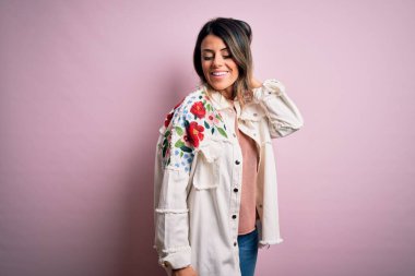 Moda kıyafetleri giyen genç ve güzel bir kadın. Manken, sokak tarzı giyiniyor. Pembe arka planda dikiliyor.