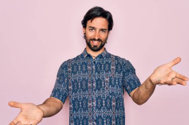 Genç, yakışıklı, bohem, pembe arka planda hippi tarzı giyinmiş neşeli gülümsemeli, yardım eli uzatan ve kabul gören bir adam..