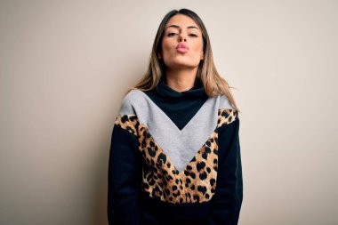 İzole edilmiş beyaz arka planda dikilip havada öpüşen kameraya bakan hoş ve seksi, genç ve güzel bir kadın. Aşk ifadesi.