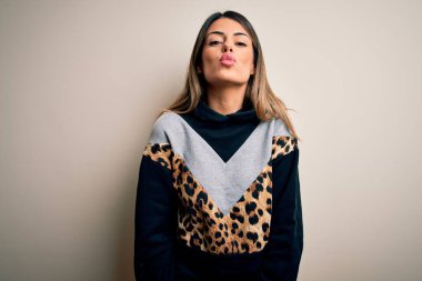 Young beautiful woman wearing casual sweatshirt standing over isolated white background looking at the camera blowing a kiss on air being lovely and sexy. Love expression. clipart