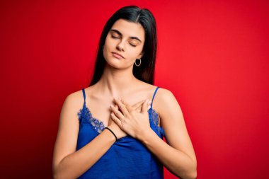 Genç ve güzel esmer kadın zarif ve rahat iç çamaşırları giyiyor. Elleri göğsünde, gözleri kapalı gülümsüyor ve yüzünde minnet ifadesi var. Sağlık kavramı.