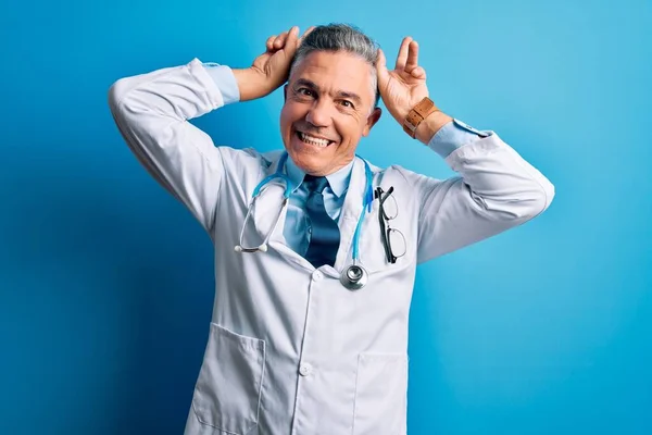 Średniego Wieku Przystojny Siwowłosy Lekarz Płaszczu Niebieskim Stetoskopie Pozowanie Śmieszne — Zdjęcie stockowe