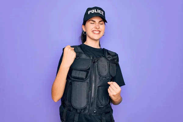 年轻的女警察身穿紫色背景的防弹背心制服 举手表决 对成功感到惊奇和惊奇 并闭上眼睛 赢的概念 — 图库照片