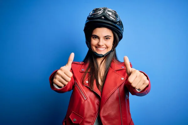 若い美しいブルネットのオートバイのヘルメットとジャケットを身に着けているオートバイの女性は 手で肯定的なジェスチャーを行うことを承認し 親指を上げて笑顔と成功のために幸せ 勝者のジェスチャー — ストック写真