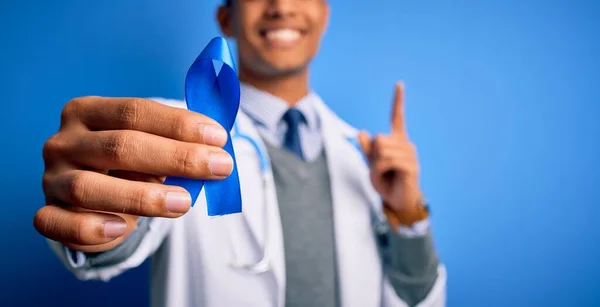 Mladý Pohledný Africký Americký Lékař Muž Držící Modrý Symbol Rakoviny — Stock fotografie