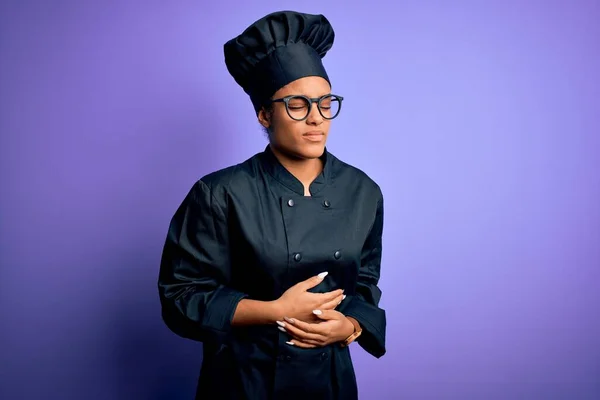 Young african american chef girl wearing cooker uniform and hat over purple background with hand on stomach because indigestion, painful illness feeling unwell. Ache concept.