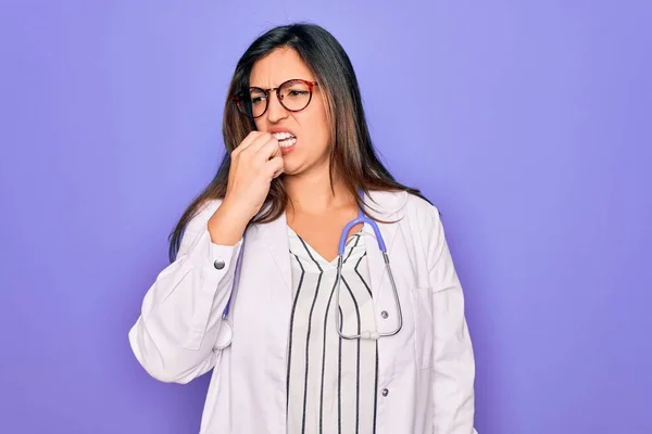 직업적 의사인 여자가 청진기를 보라색 코트를 모습은 손톱을 물면서 스트레스와 — 스톡 사진