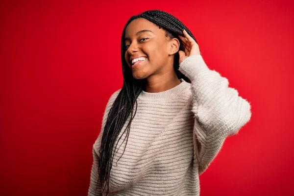 年轻的非洲裔美国女人穿着宽松的冬季毛衣 披着红色孤立的背景 双手相对地微笑 聆听流言或流言蜚语 失聪的概念 — 图库照片