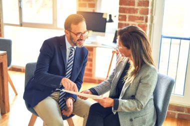 Mutlu ve kendinden emin gülümseyen iki orta yaşlı iş adamı. Ofisteki belgeleri okurken gülümseme ile birlikte çalışmak.