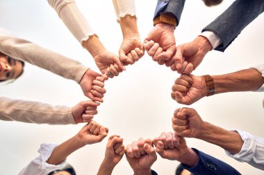 Bir grup işçi ofiste yumruk tokuşturuyor.