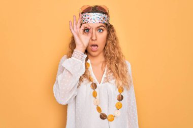 Mavi gözlü, güneş gözlüğü takan ve aksesuar takan genç, güzel sarışın hippi kadın şaşırmış yüzüyle, gözleriyle parmaklarından bakıyor. İnançsız ifade.