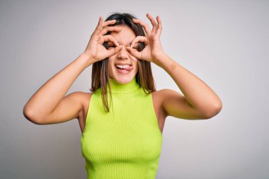 Genç, güzel, esmer bir kız, izole edilmiş beyaz bir arka planı olan günlük bir tişört giyiyor. Komik bir yüzü var.