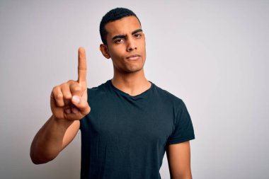 Genç ve yakışıklı Afro-Amerikalı bir adam beyaz arka plan üzerinde dikilmiş parmağını kaldırmış ve kızgın bir ifade sergiliyor.