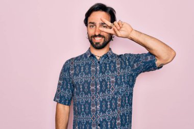 Pembe arka planda hippi tarzı giyinmiş genç, yakışıklı bohem bir adam. Yüzünde parmaklarıyla barış sembolü yapıyor. Neşeli bir şekilde zafere gülüyor.