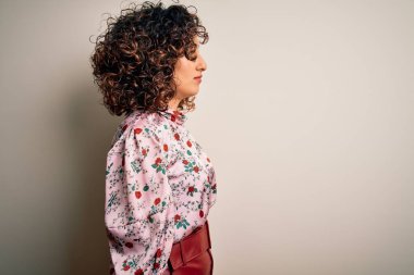 Güzel kıvırcık Arap kadın çiçekli tişört giyiyor. İzole edilmiş beyaz arka plan üzerinde duruyor. Yan tarafa bakıyor..