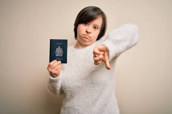 若いダウン症候群の観光客の女性は怒っている顔を持つ旅行文書としてカナダのパスポートを保持します 親指ダウンで嫌いを示す負の記号 拒絶概念 — ストック写真