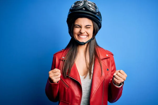 腕を上げて成功のために興奮したオートバイのヘルメットとジャケットを身に着けている若い美しいブルネットのオートバイの女性と目は笑顔で勝利を祝う閉じました 勝者のコンセプト — ストック写真