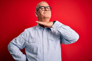 Orta yaşlı yakışıklı, beyaz gömlekli ve gözlüklü, kırmızı arka planda boğazı bıçak gibi kesen, saldırganlığı şiddetli bir şiddetle tehdit eden bir adam.