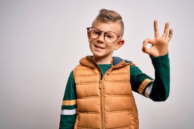 Mavi gözlü, kışlık paltolu, akıllı gözlüklü, gülümseyen, el ve parmaklarıyla imza atan beyaz bir çocuk. Başarılı ifade.