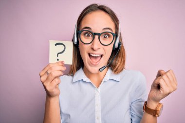 Güzel çağrı merkezi ajanı kadın elinde kulaklıkla çalışıyor. Soru işareti ile gururla bağırıyor, zaferi ve başarıyı kutluyor. Çok heyecanlı, coşkulu bir duygu.