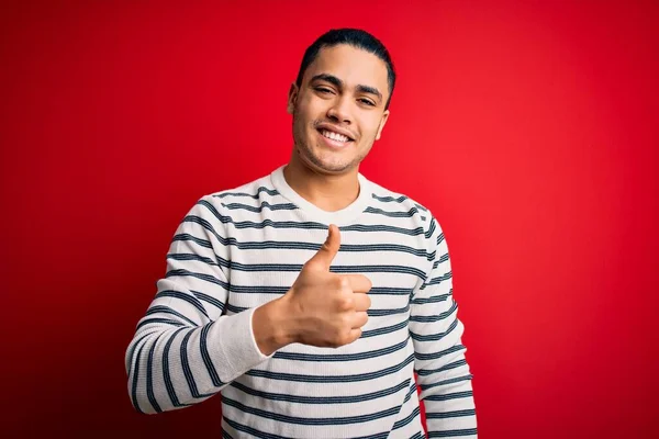 Jovem Brasileiro Vestindo Camiseta Listrada Casual Sobre Fundo Vermelho Isolado — Fotografia de Stock