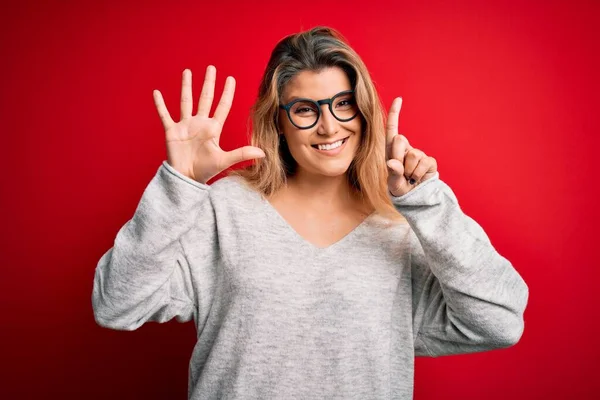 Jovem Mulher Loira Bonita Vestindo Suéter Óculos Sobre Fundo Vermelho — Fotografia de Stock