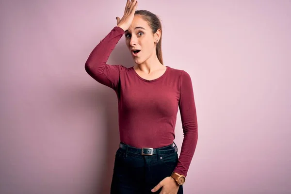 Young beautiful woman wearing casual t-shirt standing over isolated pink background surprised with hand on head for mistake, remember error. Forgot, bad memory concept.