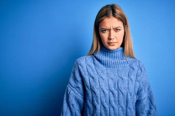 青の隔離された背景に冬のウールのセーターを身に着けている若い美しいブロンドの女性は落ち込んでおり 苦痛を心配し 怒って恐れている 悲しい表情 — ストック写真