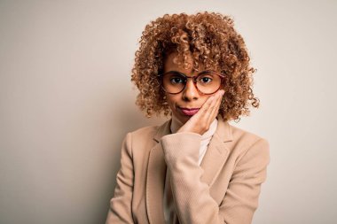 Güzel afro-amerikan iş kadını gözlük takıyor beyaz arka planda, kollarını kavuşturup depresyondan sıkılmış ve yorgun görünüyor..