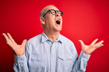 Orta yaşlı yakışıklı, beyaz bir adam kırmızı arka plan üzerinde gözlük takıyor. Deli gibi bağırıyor, agresif bir ifade ve kollarla bağırıyor. Hayal kırıklığı konsepti.