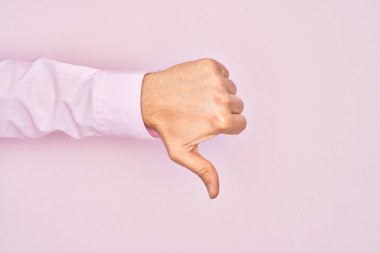 Kafkas 'lı genç adam parmaklarını pembe arka planda gösteriyor. Başparmak işareti yapıyor. Reddetme hareketi, onaylamama ve olumsuz işaret yapıyor.