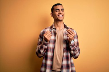 Genç, yakışıklı, Afro-Amerikalı bir adam sarı arka planda dikilmiş, para jesti yapıyor, maaşını istiyor, milyonerlik işi yapıyor.