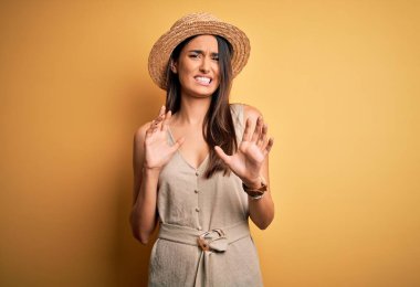 Genç ve güzel esmer kadın tatilde. Günlük elbise ve şapka takıyor. Tiksindirici tepki verdiği için rahatsız edici ve korkunç bir ifade takınıyor. Eller havada