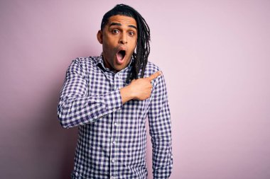 Rastgele gömlek giyen Afro-Amerikan genç, yakışıklı Afro-adam. Yan tarafı göstererek şaşırmış, ağzı açık, şaşkın bir ifade..