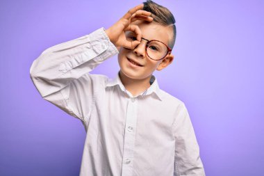 Mor arka planda mavi gözlü, beyaz gömlekli, beyaz gözlü küçük beyaz bir çocuk el hareketleriyle gülümsüyor ve mutlu yüzüyle parmaklarının arasından bakıyor..