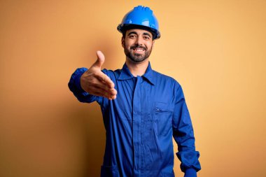 Sakallı, mavi üniformalı ve sarı arka planda kasklı tamirci dostça bir selamlama ve hoş geldin hediyesi olarak gülümsedi. Başarılı bir iş..