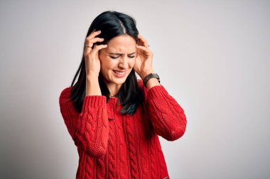 Mavi gözlü genç esmer kadın izole edilmiş beyaz arka planda günlük süveter giyiyor. Ağrı ve migren yüzünden baş ağrısı ve stresten muzdarip. Ellerini başının üstüne koy..