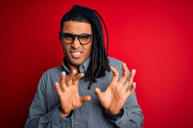 Rastgele gömlek ve gözlük takan, tiksindirici ifade takınan, tiksindirici tepki verdiği için tiksindirici ve korku dolu genç, Afro-Amerikan erkeği. Eller havada