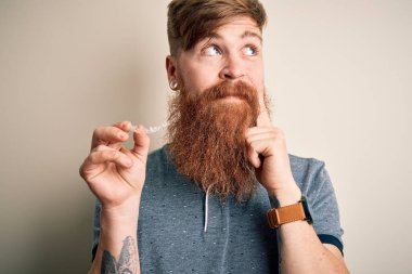 Dişlerinin düzeltilmesi için diş teli tutan kızıl saçlı İrlandalı bir adam. Ciddi bir yüz ifadesi var. Soru sormayı düşünüyor.