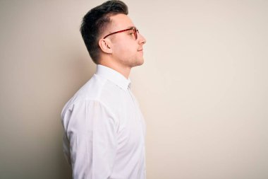 Genç yakışıklı iş adamları gözlük takıyor ve zarif gömlekler giyip yalıtılmış arka plana bakıyor, rahat profil pozu veriyor ve kendine güvenen bir gülümseme takınıyor..