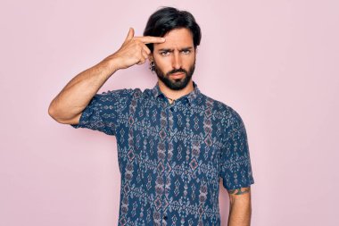 Pembe arka planda hippi tarzı giyinmiş genç, Latin asıllı bohem bir adam alnında sivilceden mutsuz, siyah noktalı çirkin bir enfeksiyon olduğunu gösteriyor. Sivilce ve deri problemi