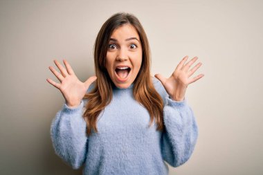 Kış süveteri giymiş genç ve güzel bir kadın izole arka planda durmuş çılgın ve hayret verici bir başarıyı kollarını kaldırıp heyecanla haykırarak kutluyor. Kazanan konsept