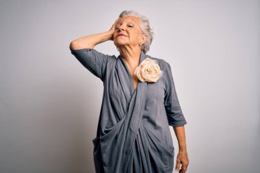 Son sınıf güzeli, gri saçlı, sıradan bir elbise giyen beyaz arka planda duran, kendine güvenen, el hareketleriyle saçlarına dokunan, çekici ve modaya uygun poz veren bir kadın.