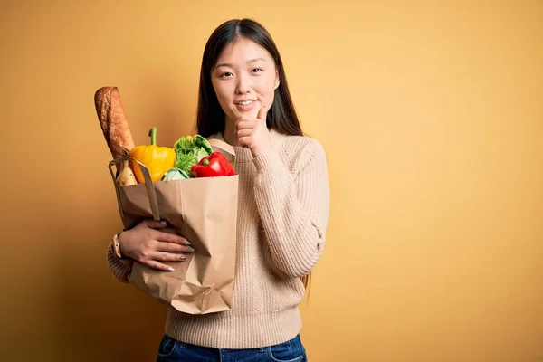 Mladá Asiatka Drží Papírový Sáček Čerstvými Zdravými Potravinami Nad Žlutým — Stock fotografie