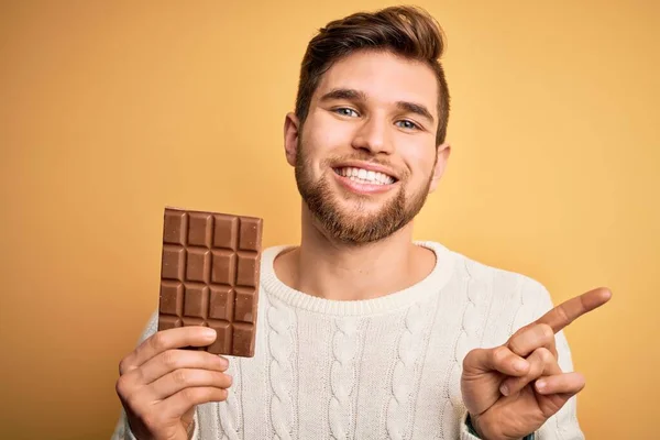 Jovem Loiro Com Barba Olhos Azuis Segurando Barra Chocolate Sobre — Fotografia de Stock