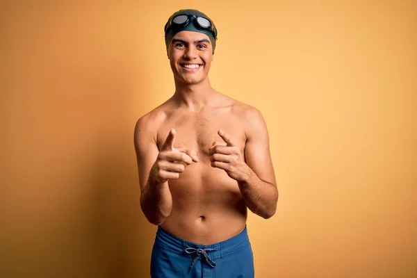 Jonge Knappe Man Shirtloos Zwempak Badmuts Geïsoleerde Gele Achtergrond Wijzende — Stockfoto