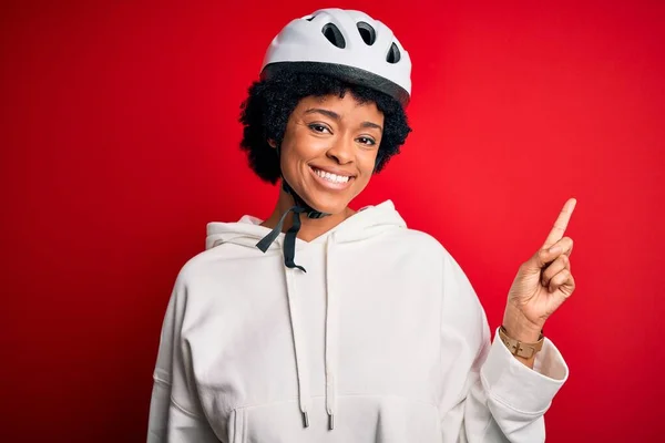 年轻的非洲裔美国人骑自行车的女人 戴着自行车安全帽 脸上挂着大大的笑容 手指手画脚地看着摄像机的侧面 — 图库照片