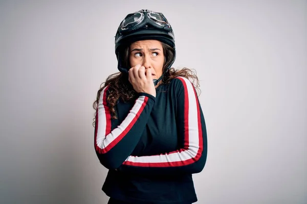 白い背景の上に元ヘルメットを身に着けている巻き毛を持つ美しいオートバイの女性は 口の上に爪をかむ上で手で強調し 緊張している 不安の問題 — ストック写真