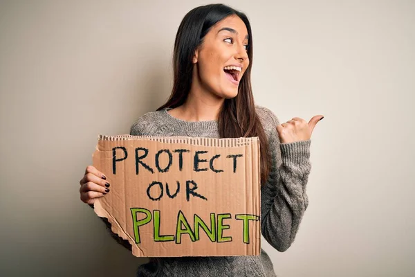 若いです美しいブルネットアクティビスト女性抗議のために保護するために私たちの惑星保持ポスターポインティングと表示で親指で側に幸せな顔笑顔 — ストック写真
